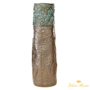 Jarrón de cerámica cilíndrico con apariencia de pátina sobre bronce.